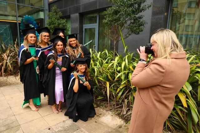 Female taking a photo of a group of female graduates