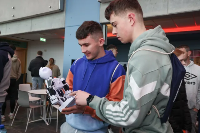 2 male students looking at a robot