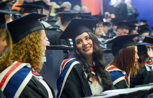 Two female students sitting at Conferring ceremony