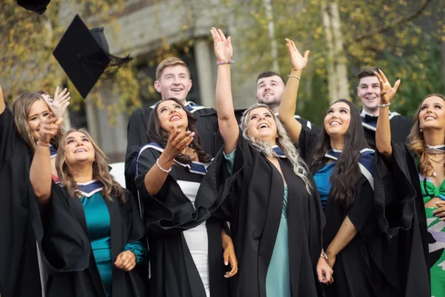 Group of male and female students throwing Graduation caps in the air