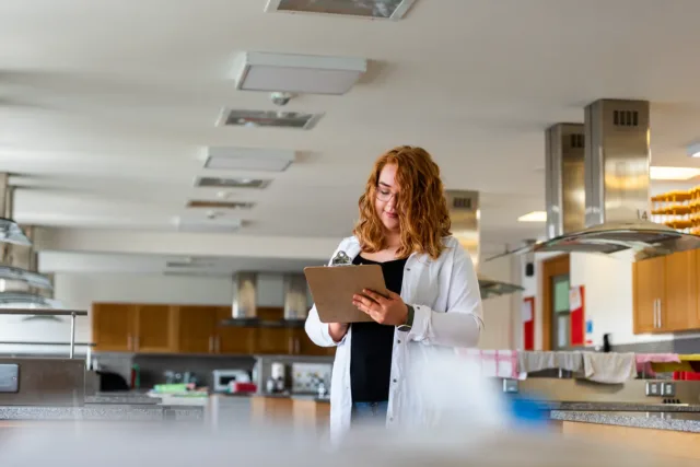 Female student in kitchen wearing lab coat Lydia