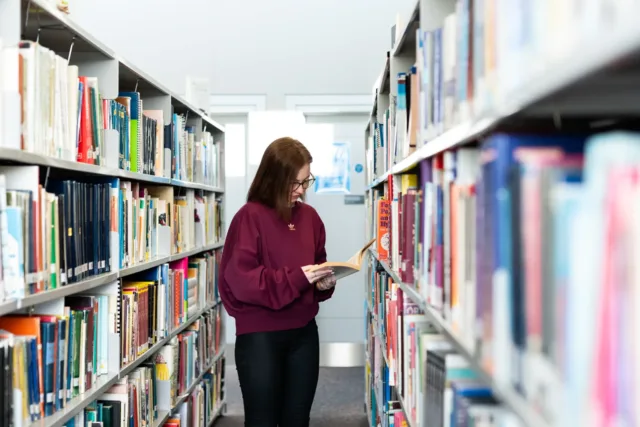 Female student reading book in library