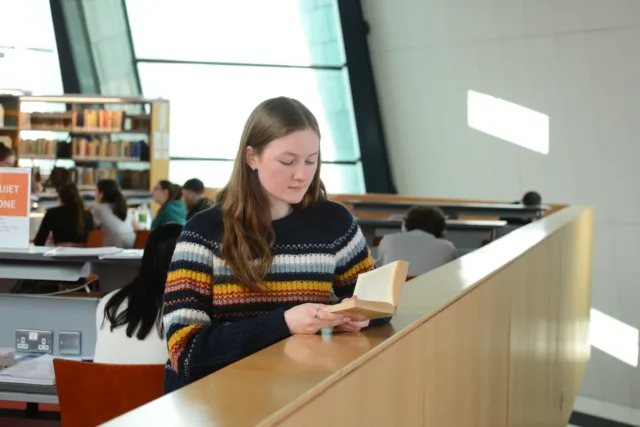 Female student reading book in library