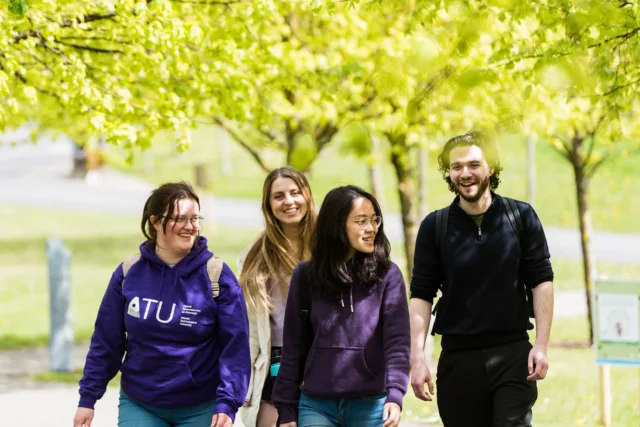 A group of students laughing while walking around the campus