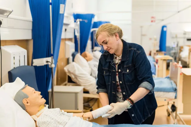 A student nurse practices bandaging on a dummy