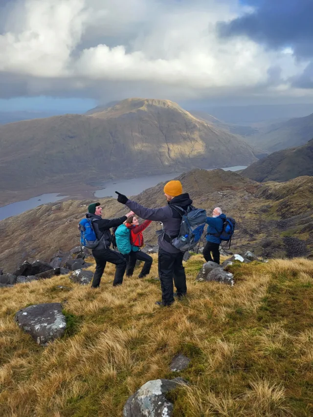 Students are laughing whilst at the top of a large hill all wearing hiking gear