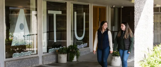 students walking outside mountbellew campus with ATU logo on window in background