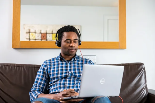 Student sitting with a laptop and wearing headphones