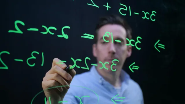 Student writing an equation on a glass board