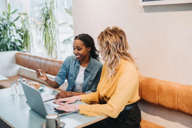 Students looking at a laptop in a cafe