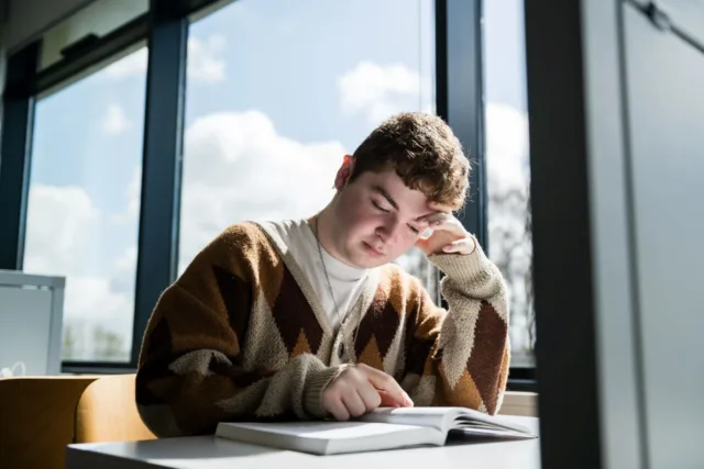 Student studies a textbook in the University library