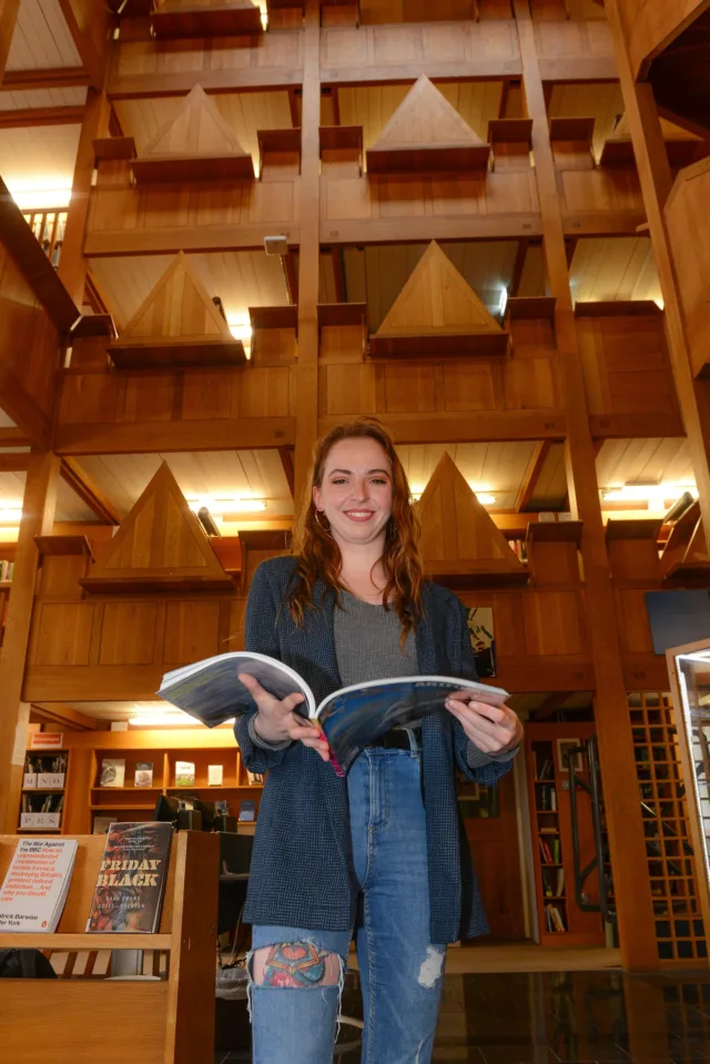 Female student holding a book in library