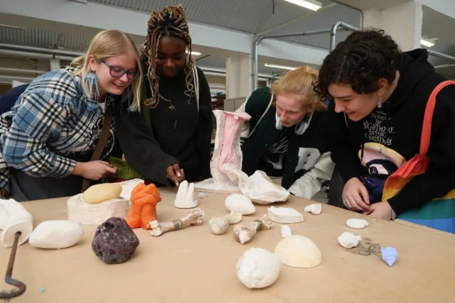 5 female students looking at ceramics on a table