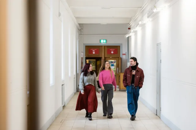 2 female students and one male student walking in hallway