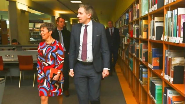 Minister Harris and Dr Orla Flynn walk through a library