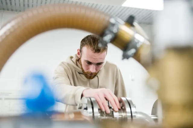 Engineering student visible through a pipe, looking down at his work