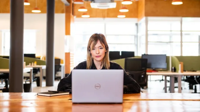 A person sitting at a desk, wearing headphones and working on a laptop.