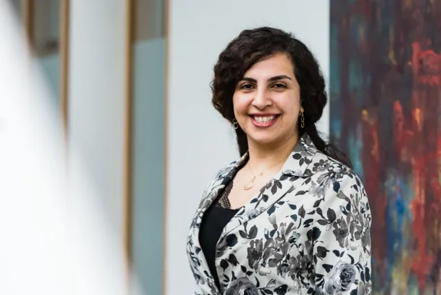 Mature student stands in front of colourful abstract painting