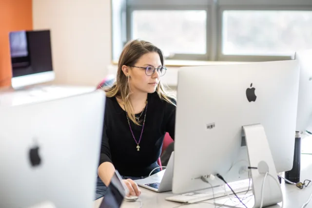 Female student sitting in MAC computer lab working on Apple Computer