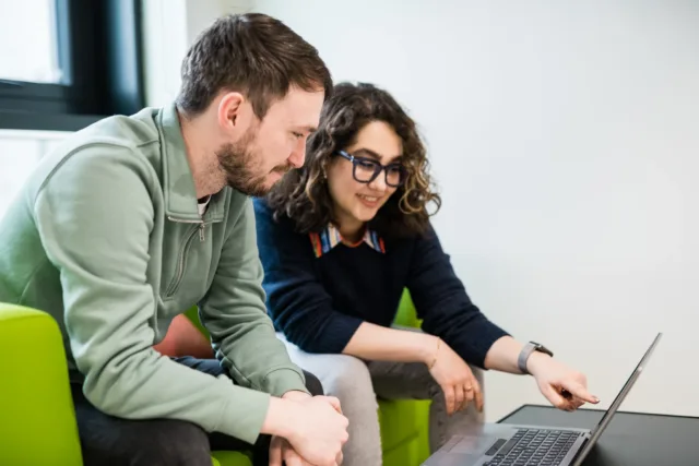 Male and Female Student sitting on a couch looking at a laptop