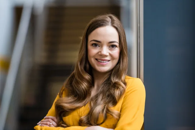 Headshot photo of female student in yellow top, arms folded