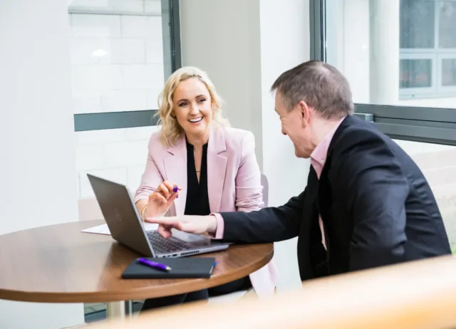 Female and Male Business student in discussion sitting at a table with open laptop