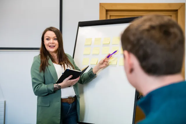 ATU Staff pointing at a white board with sticky notes applied to it