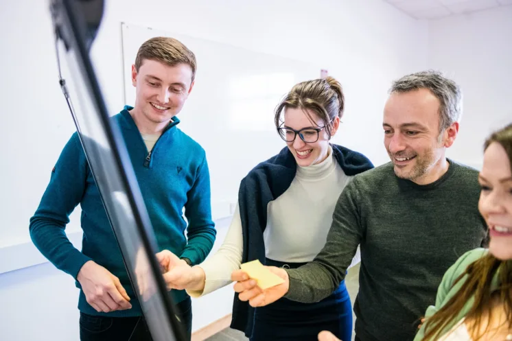 Four students collaborating at a white board