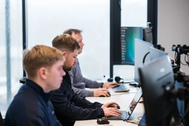 Three males in the workplace working on computers.