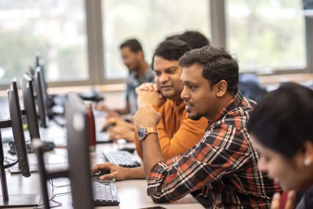 International students working together in a computer lab looking at a screen