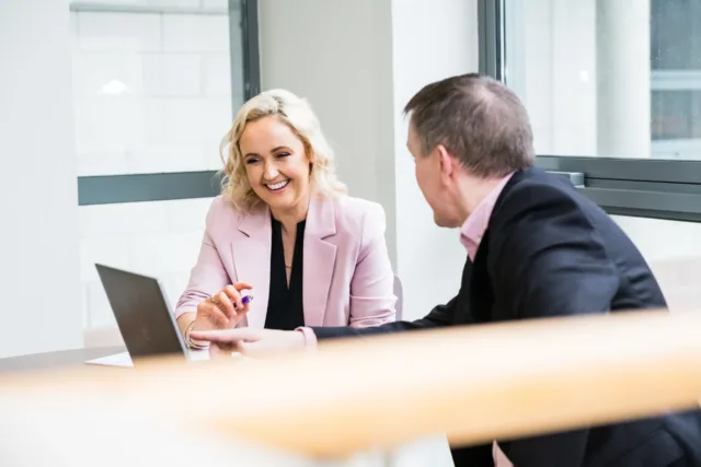 Mature students, male and female studying business at a table looking at a laptop