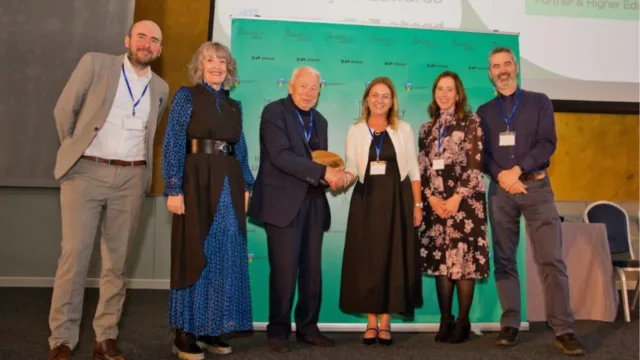 ATU's Niamh Plunkett and Maureen Haran accept the UDL Excellence in Collaboration Award alongside John Kelly, Mark Glynn, Anna Kelly, and Dara Ryder. Niamh shakes hands with John Kelly during the presentation.