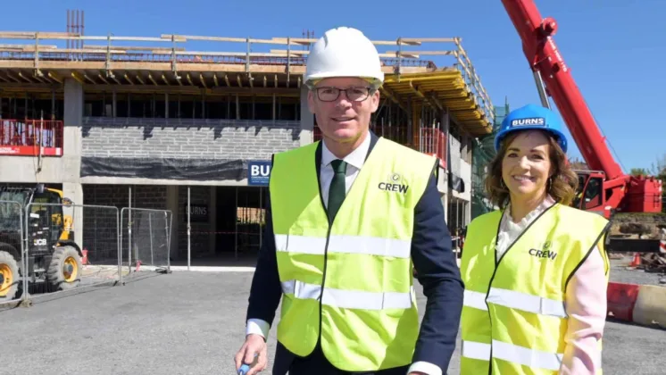 Minister Simon Coveney and Niamh Costello, CEO of CREW, participate in the brick-laying ceremony for the CREW Creative Enterprise Hub at the ATU Galway city campus on Wellpark Road. The image captures the construction phase of the project with the building site in the background.