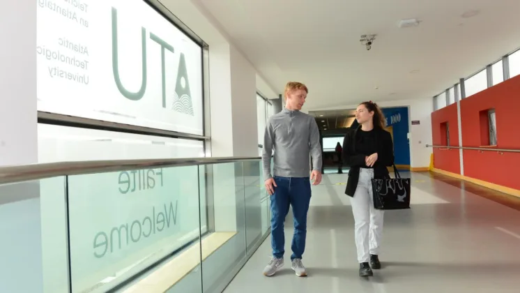 A young man and woman walk side by side down a hallway