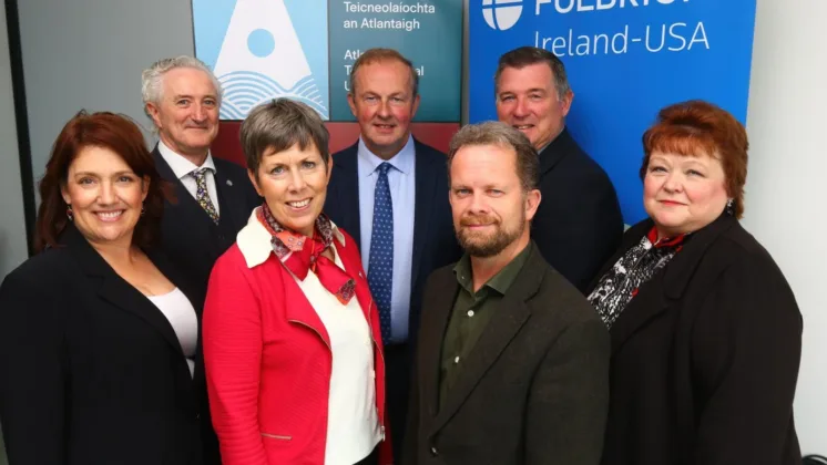 A group of people smiling and looking towards the camera, with ATU and Fulbright Ireland banners in the background.