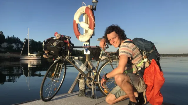 A Swedish environmental student poses with his bicycle by the water.