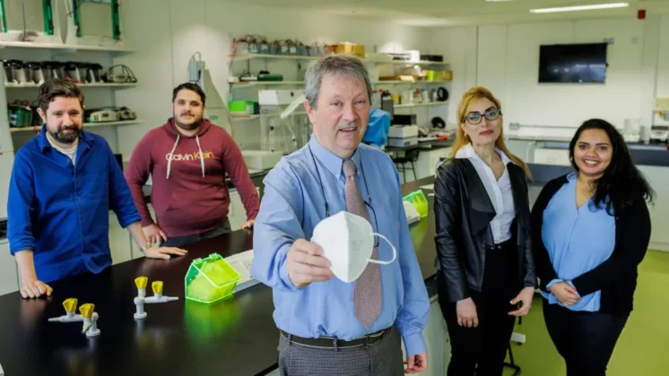 Dr Jerry Bird holds up a PPE mask with four ATU researchers in the background