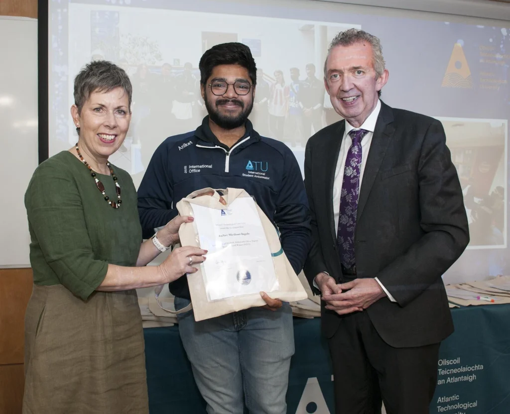 A student is pictured between ATU President Dr Orla Flynn and ATU Donegal Head of College Paul Hannigan. Dr Flynn is presenting an award to the student, who is smiling as they receive it. Both Dr Flynn and Paul Hannigan stand beside the student, also smiling.