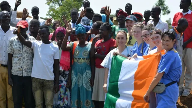 Nursing students pictured holding the Irish flag alongside villagers from Uganda.