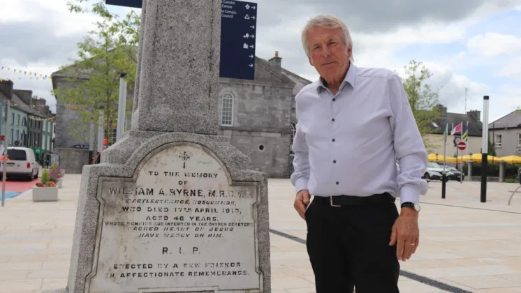 Veterinary surgeon Donal Connolly, founding member of the Aleen Cust Memorial Society, standing beside the memorial to William Augustine Byrne, MRCVS, Aleen Cust's first employer, located in Roscommon Town Square.