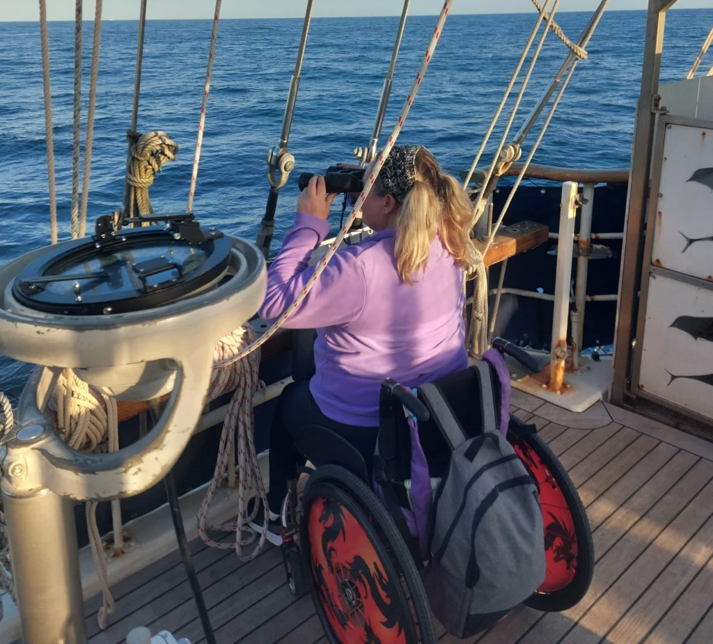 Victoria Matthews, a wheelchair user and ATU Sligo Sport with Business student, looking out through binoculars onboard a ship