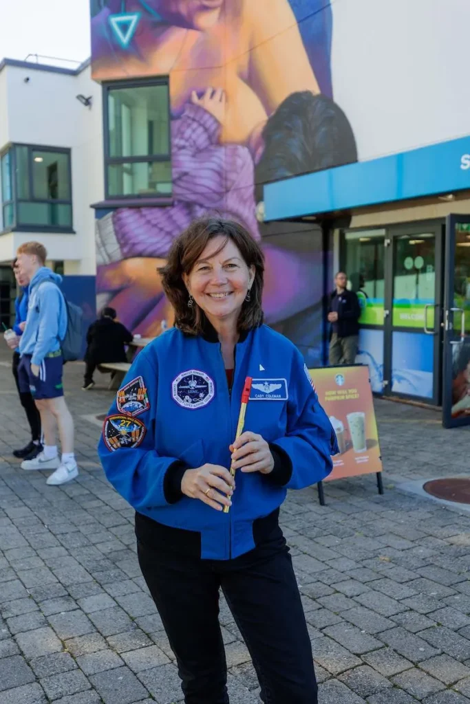 Cady Coleman holding tin whistle infront of breastfeeding mural