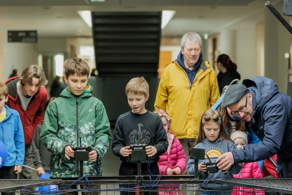 Children and parents use remotes to play move robots