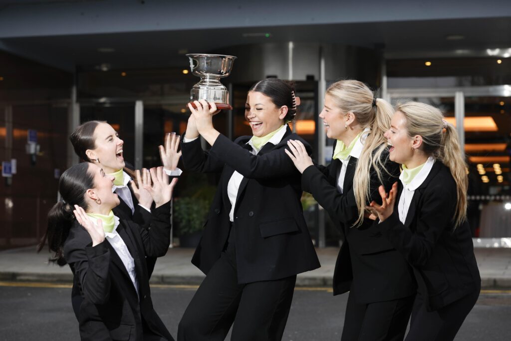 Female Hotel staff in black suits celebrating win and holding trophy