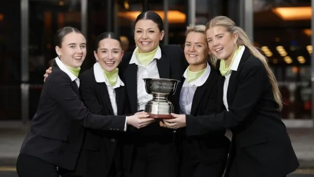 Hotel employee holding award and smiling