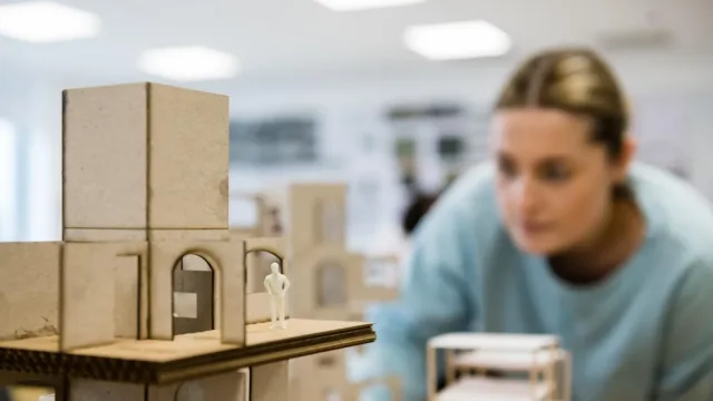 Artist inspects model of a building