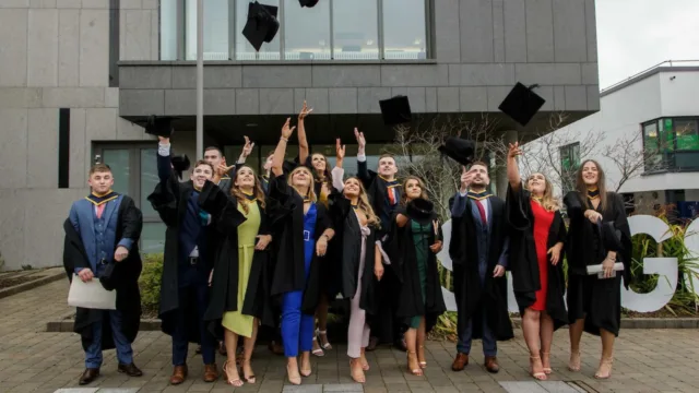 A group of graduates throws their caps in the air, celebrating their achievement