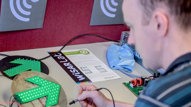 A person works on an electrical circuit to light up a green arrow.