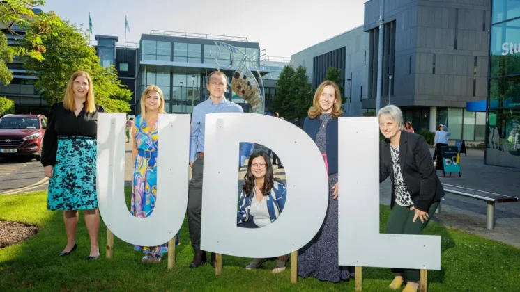 Six people standing behind large lettering that spells out 'U D L' in front of the ATU Sligo campus. The group is posing together, with the campus building visible in the background.