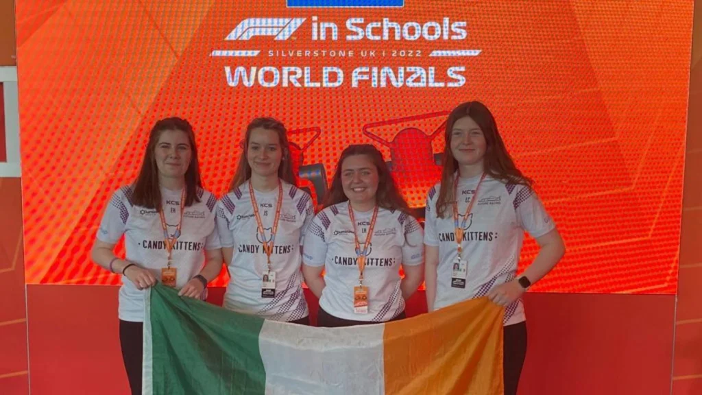 A group of four school students at the Formula 1 event in Silverstone, smiling while holding an Irish flag.